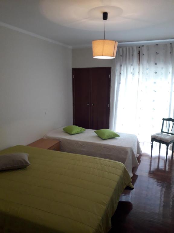 1 dormitorio con 2 camas con almohadas verdes y ventana en Apartamento 300 metros do SANTUÁRIO DE FÁTIMA T4, en Fátima