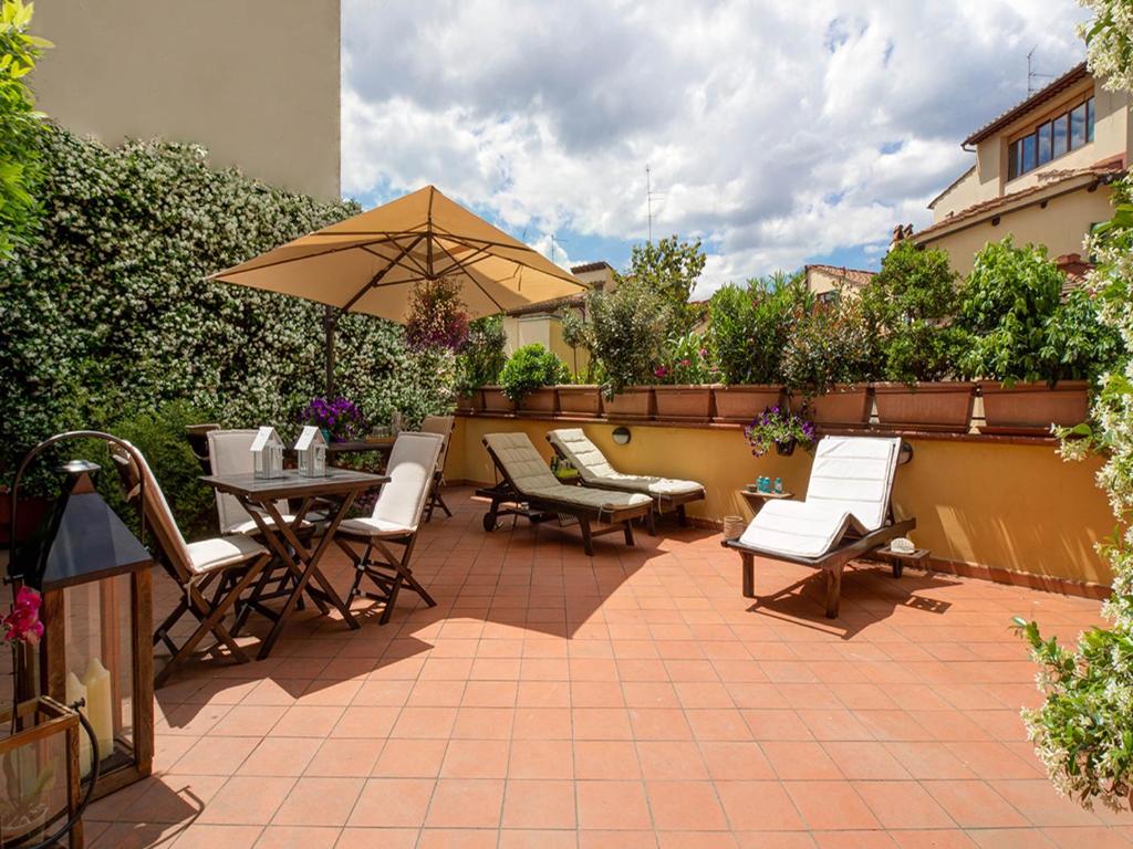 une terrasse avec une table, des chaises et un parasol dans l'établissement Your Florence, à Florence