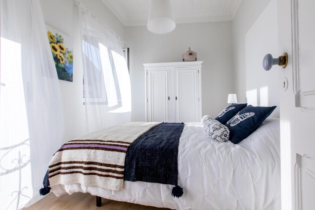 biała sypialnia z łóżkiem z niebieskimi poduszkami w obiekcie Casa do Tanque T2 w mieście Arouca