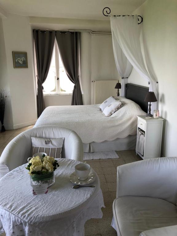 ein weißes Schlafzimmer mit einem Bett, einem Tisch und Stühlen in der Unterkunft Chambre d'hotes Romance in Saint-Jean-les-Deux-Jumeaux