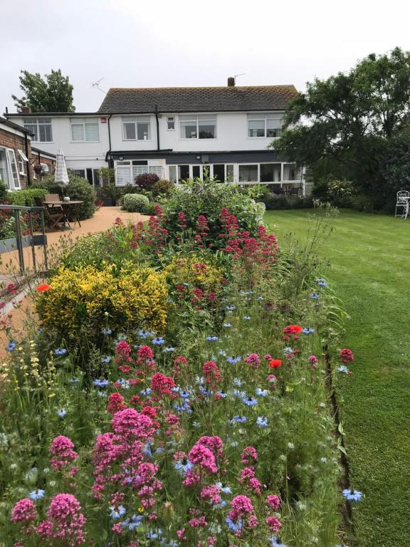 a garden with colorful flowers in front of a house at The Coast Yard B & B and Garden Chalets in Selsey