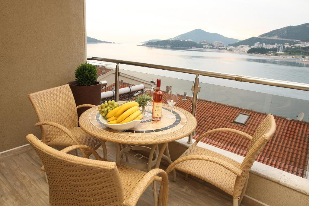 una mesa con un bol de fruta y vino en el balcón en AURA Apartments, en Budva