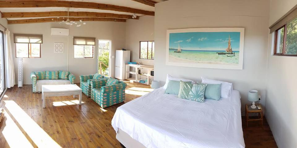 a bedroom with a bed and a living room at Dune View Cottage in Sodwana Bay