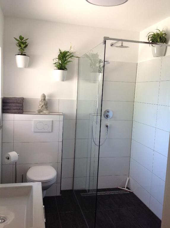 La salle de bains est pourvue d'une douche, de toilettes et de plantes en pot. dans l'établissement Kleine Oase, à Rust
