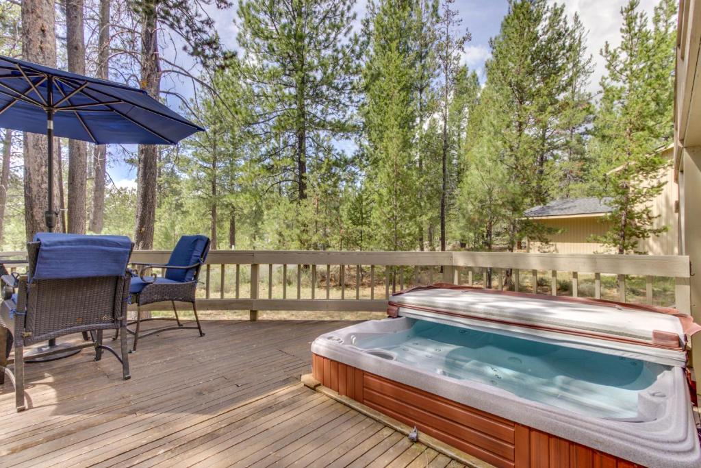 a hot tub on a deck with a table and an umbrella at Sundial on Deck in Sunriver