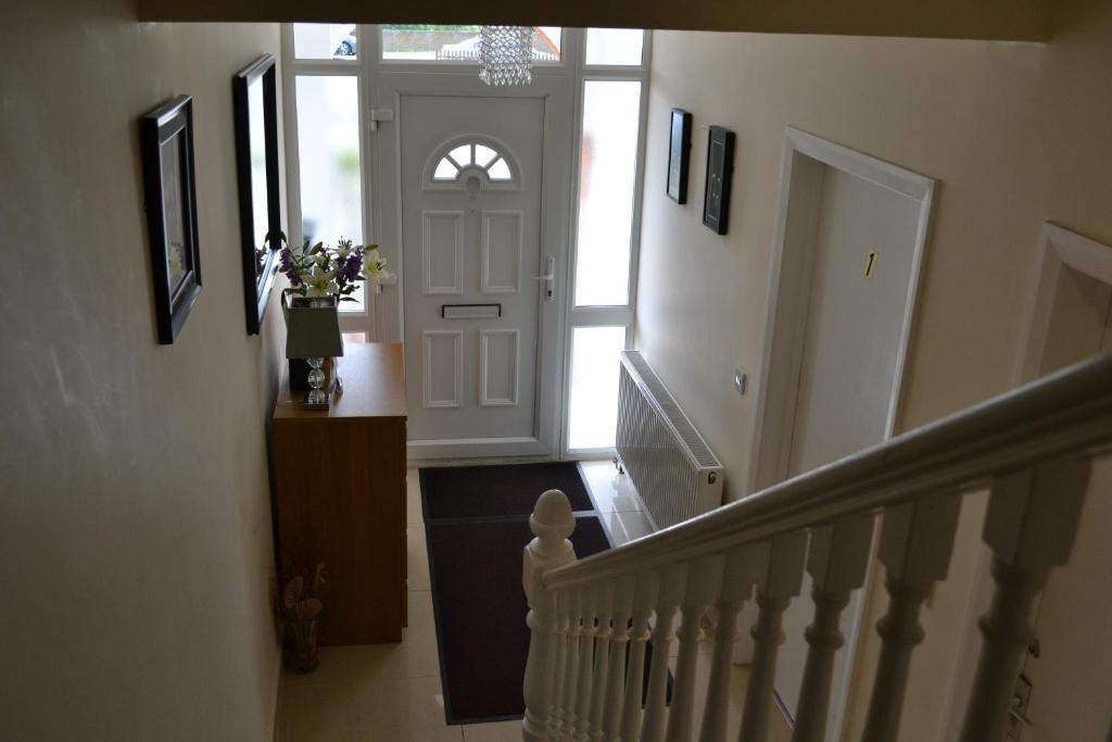 a hallway with a white door and stairs with a vase of flowers at Annie's Guest House in Farnborough