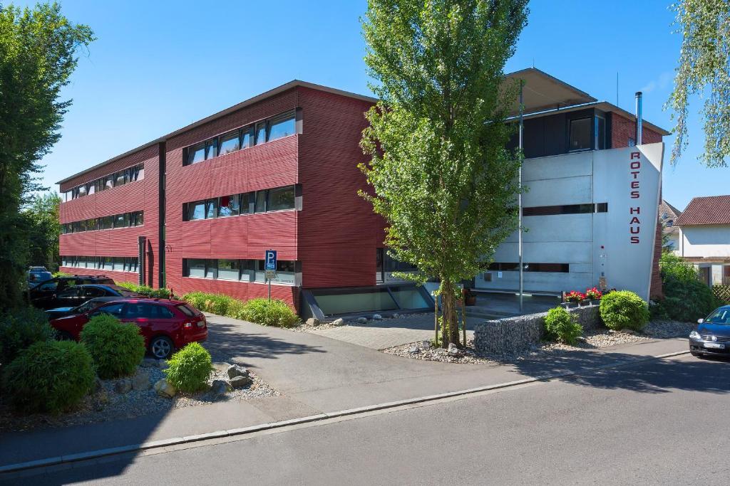 un edificio de ladrillo rojo con coches aparcados delante de él en Bed & Breakfast Rotes Haus, en Überlingen