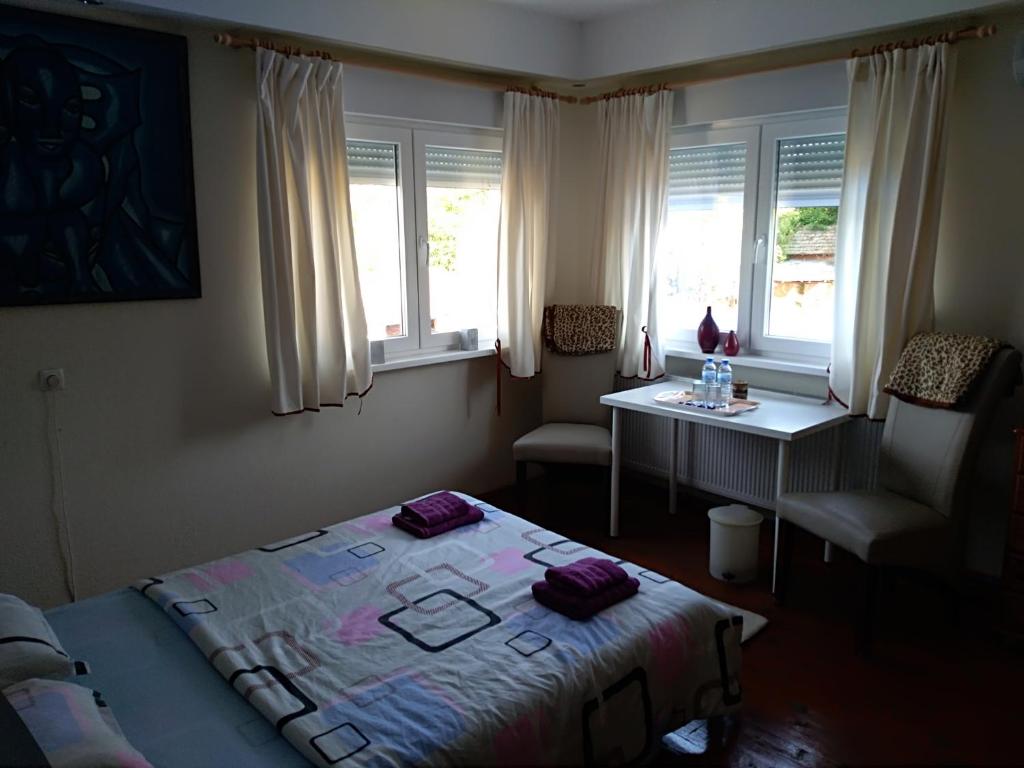 Schlafzimmer mit einem Bett, einem Tisch und Fenstern in der Unterkunft Rogozen B&B in Rogozen