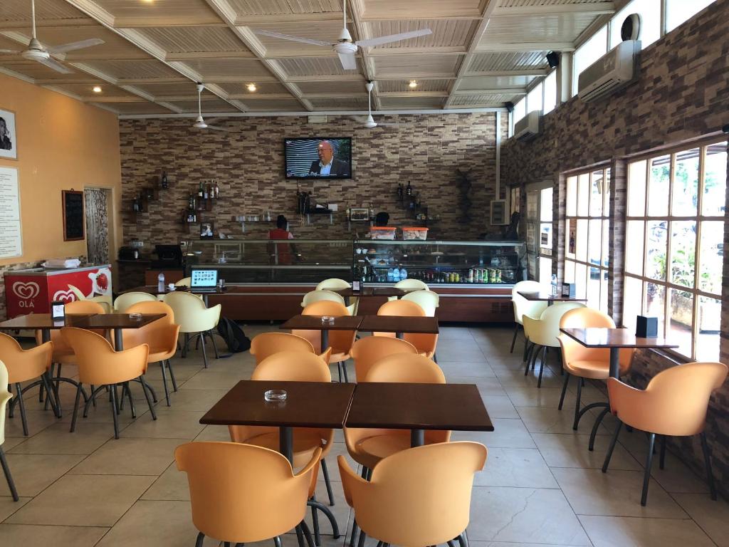 a restaurant with tables and chairs and a bar at Hotel Central in São Tomé