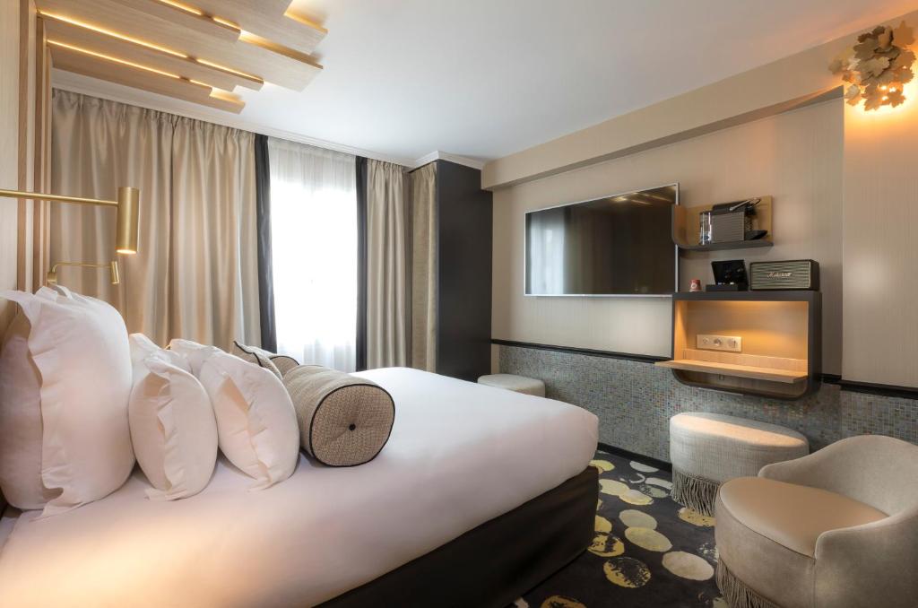 パリにあるホテル デュ カドランの大きなベッドと椅子が備わるホテルルームです。