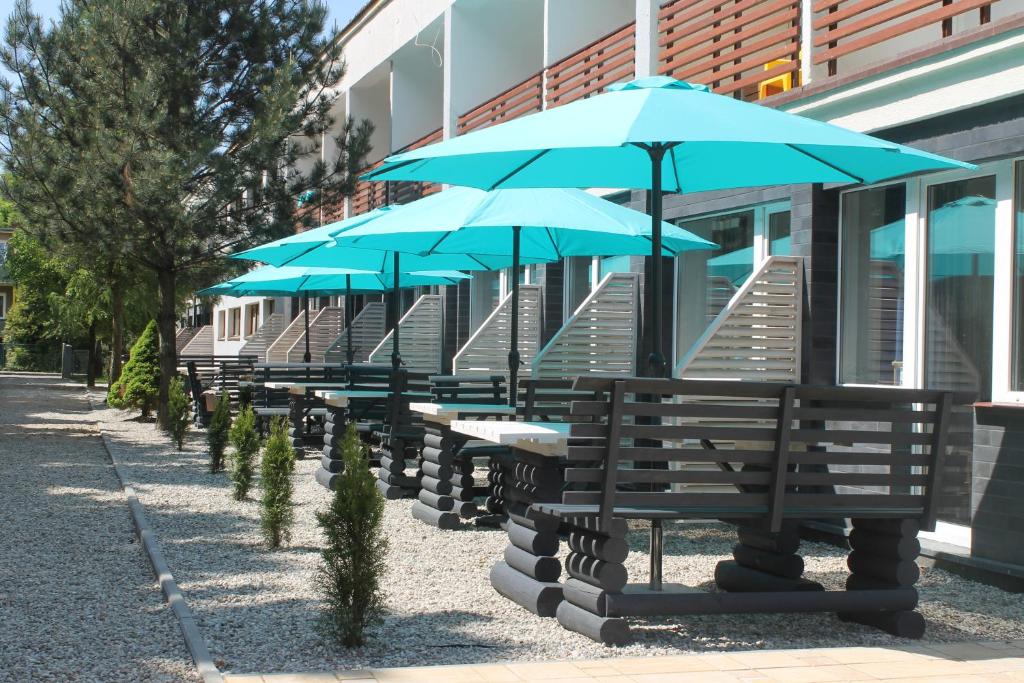 a row of benches with blue umbrellas in front of a building at Błekitne Tarasy in Ustronie Morskie