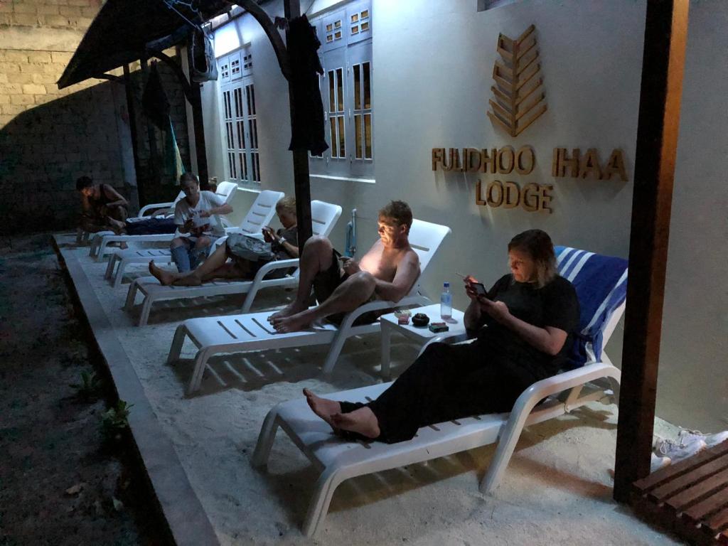 a group of people sitting on lawn chairs outside a building at Fulidhoo Ihaa Lodge in Fulidhoo