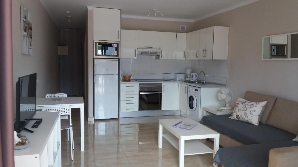 a small kitchen and living room with white cabinets at Departamento Barcaro 2 in Puerto del Carmen