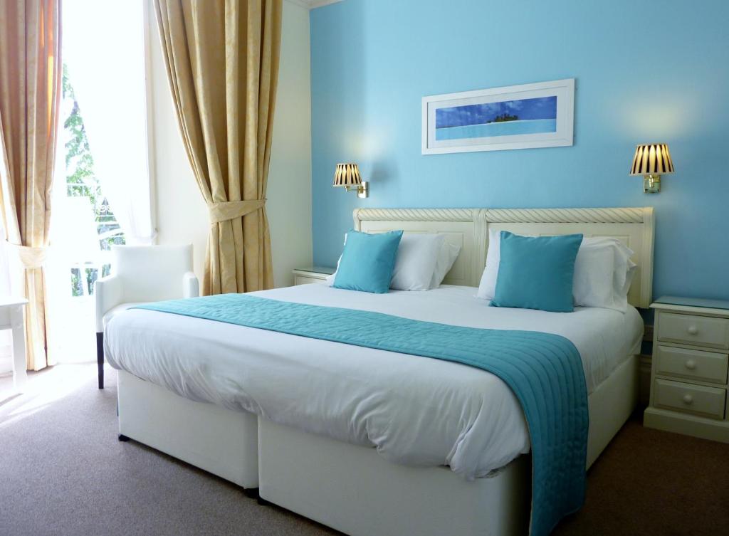 a bedroom with a large bed with blue walls at The Iona in Torquay