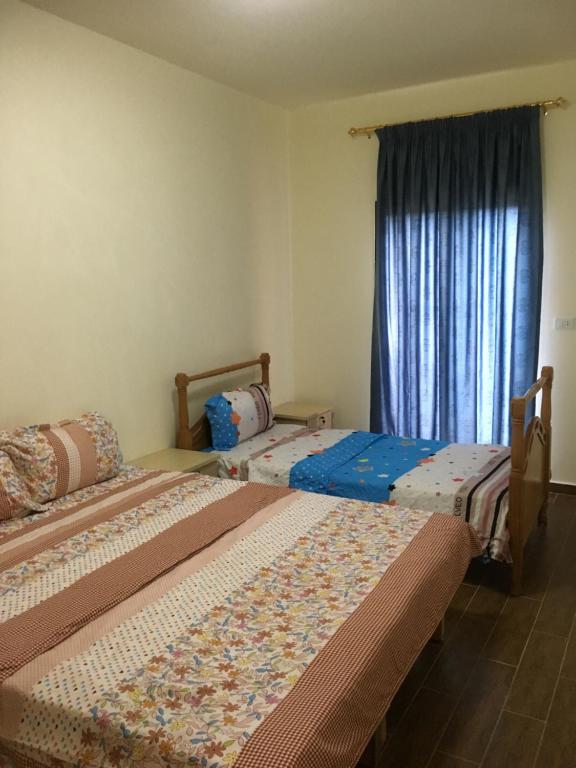 two beds in a room with a window at Koura Nahla Apartment in An Nakhlah