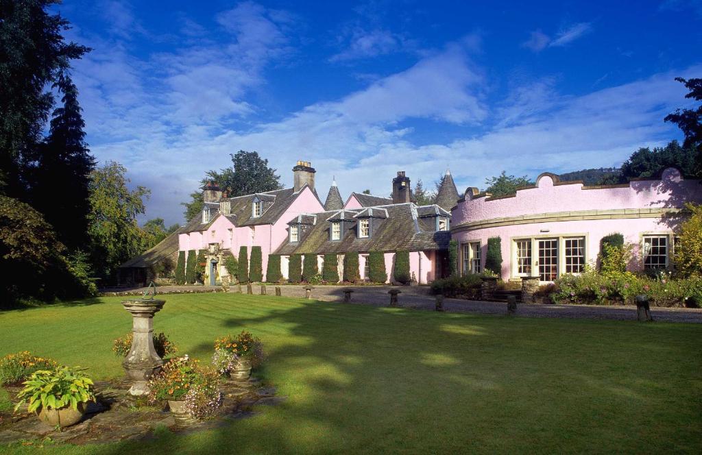 uma casa grande com um relvado verde em frente em Roman Camp Country House Hotel em Callander