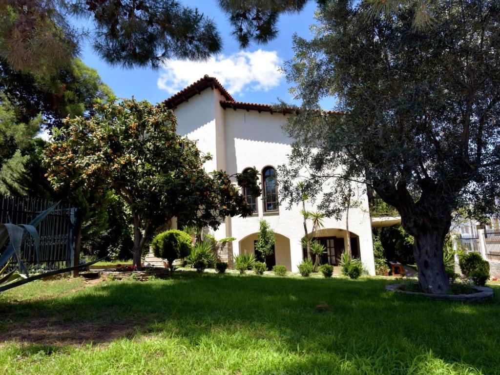 a white house with a tree in the yard at Ares Garden House - Nea Moudania Halkidiki in Nea Moudania