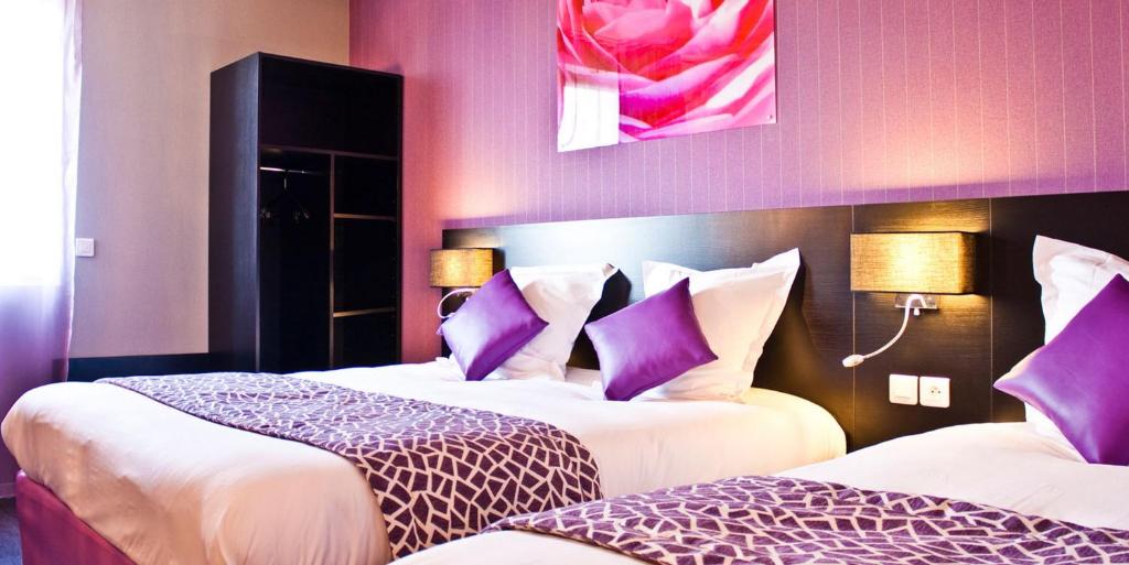 um quarto de hotel com duas camas com almofadas roxas em The Originals City, Hôtel des Lys, Dreux (Inter-Hotel) em Dreux