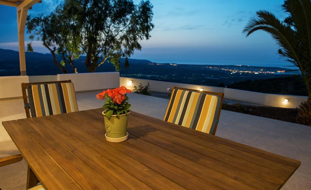 een houten tafel met een vaas met bloemen erop bij Sitia Balcony View in Sitia