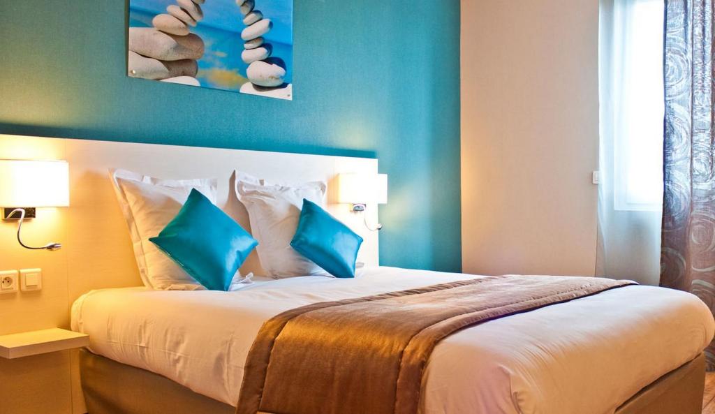 a bedroom with a large bed with blue walls at The Originals City, Hôtel des Lys, Dreux in Dreux