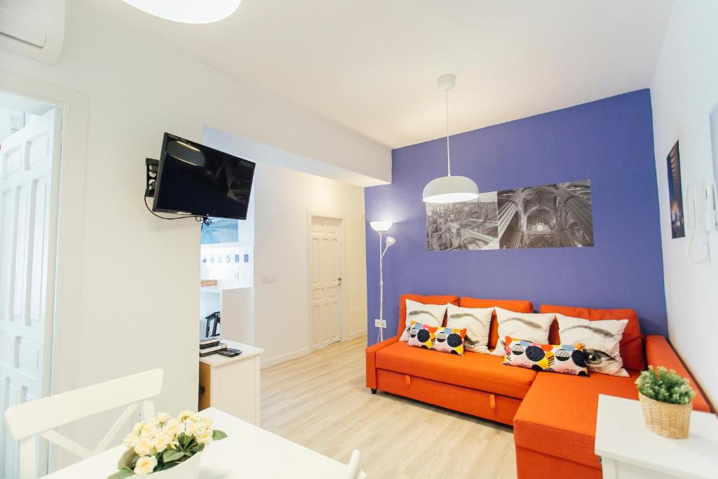 un salon avec un canapé orange et un mur bleu dans l'établissement Colorful and diaphanous- 3Bd 1Bth - Peral, à Séville
