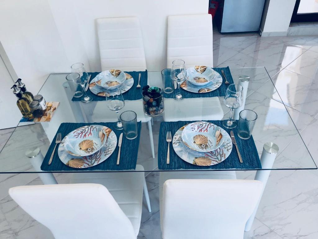 a glass table with plates and glasses on it at "Sea Stars" Luxury Central Apartment in Varna City