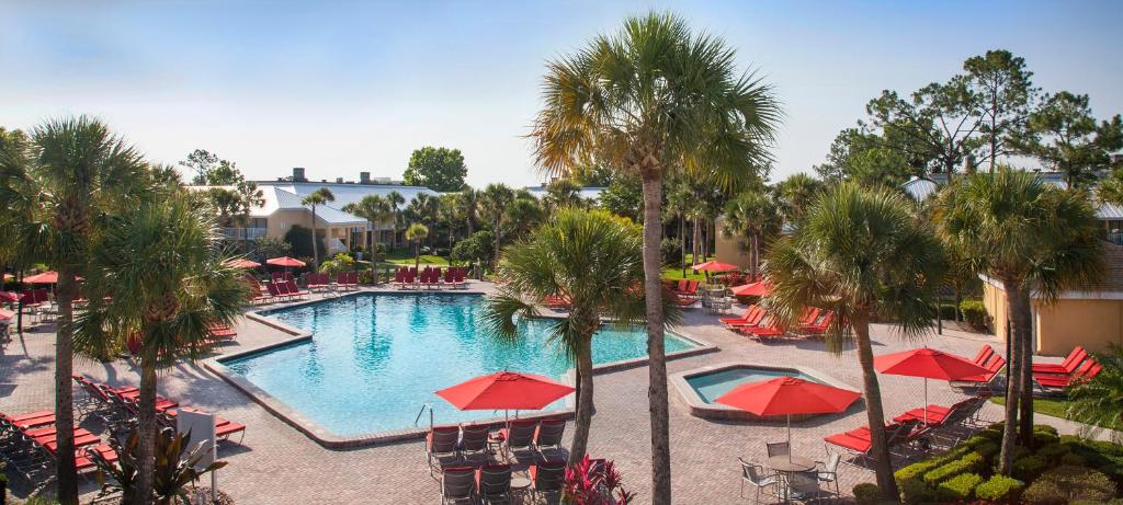 a pool with red umbrellas and chairs and palm trees at Wyndham Orlando Resort International Drive in Orlando