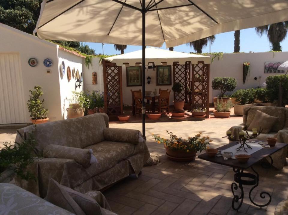 a patio with a couch and an umbrella at casa vacanze Sciaraba in Mazara del Vallo