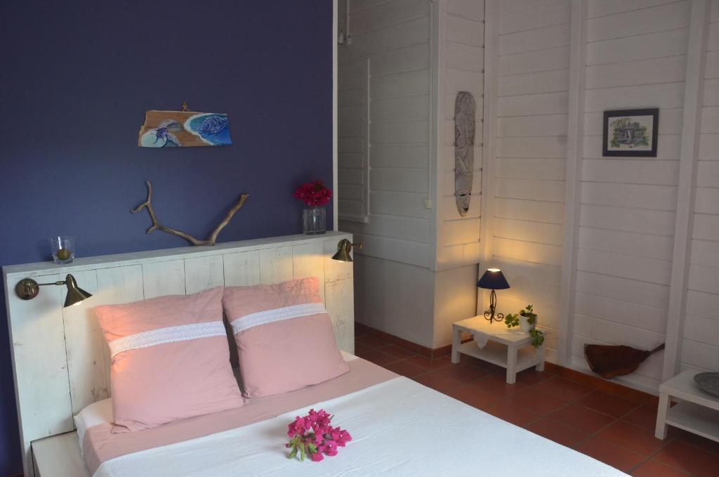 a bedroom with a white bed with pink pillows at La Case Dentelle in Le Diamant