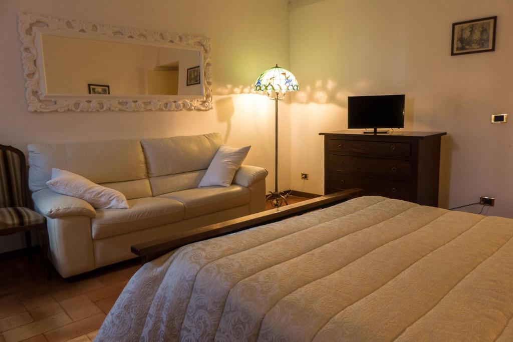 a bedroom with a bed and a couch and a mirror at Villa Montotto in Monterubbiano