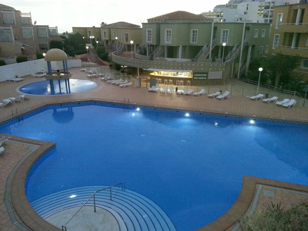 een groot blauw zwembad met stoelen en gebouwen bij Apartamento Orlando in Adeje