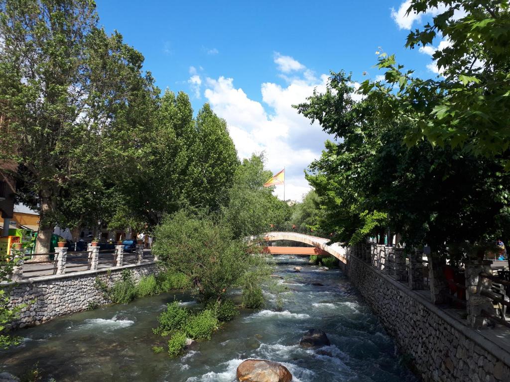 a river with a bridge and people walking on the side at Apartamento Erillas in Pinos Genil