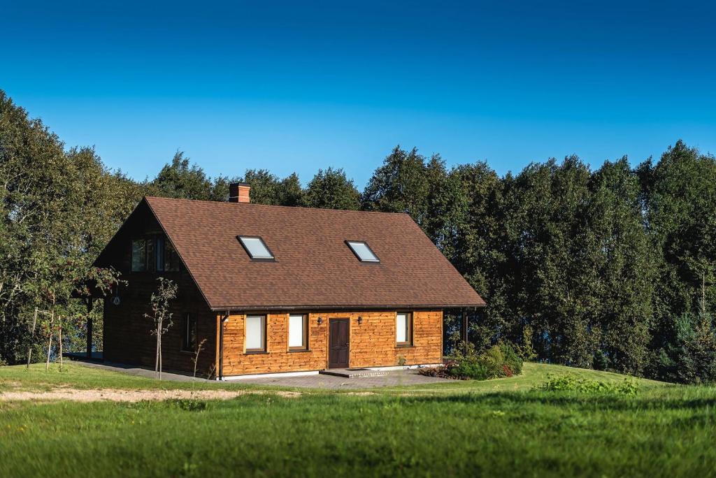 a brick house with a brown roof in a field at Lakeside holiday house "Beavers" Bebruciems in Leitāni