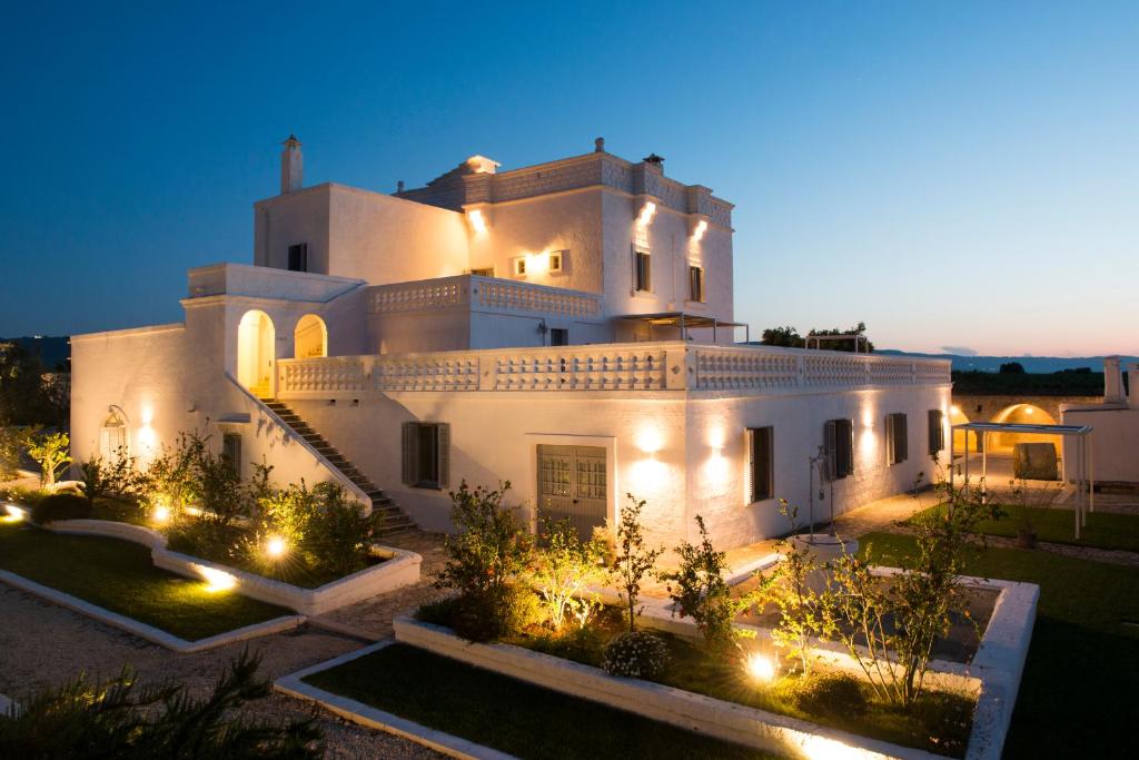 duży biały budynek z oświetleniem przed nim w obiekcie Masseria San Giovanni - Epoca Collection w mieście Fasano