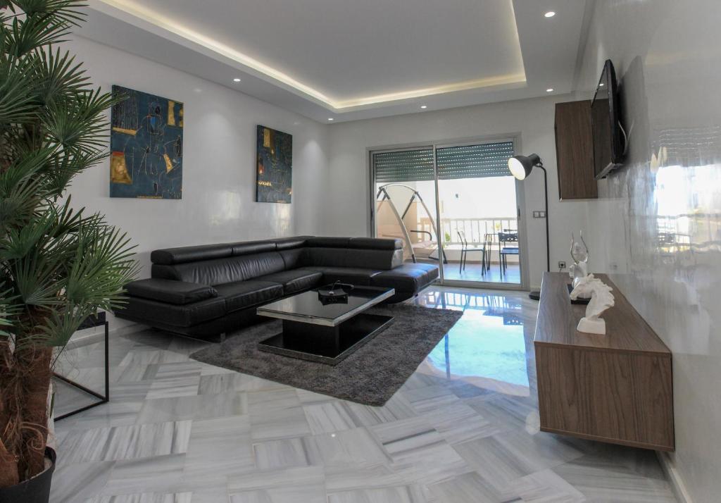 a living room with a black leather couch and a table at La Siesta Beach Resort in Mohammedia