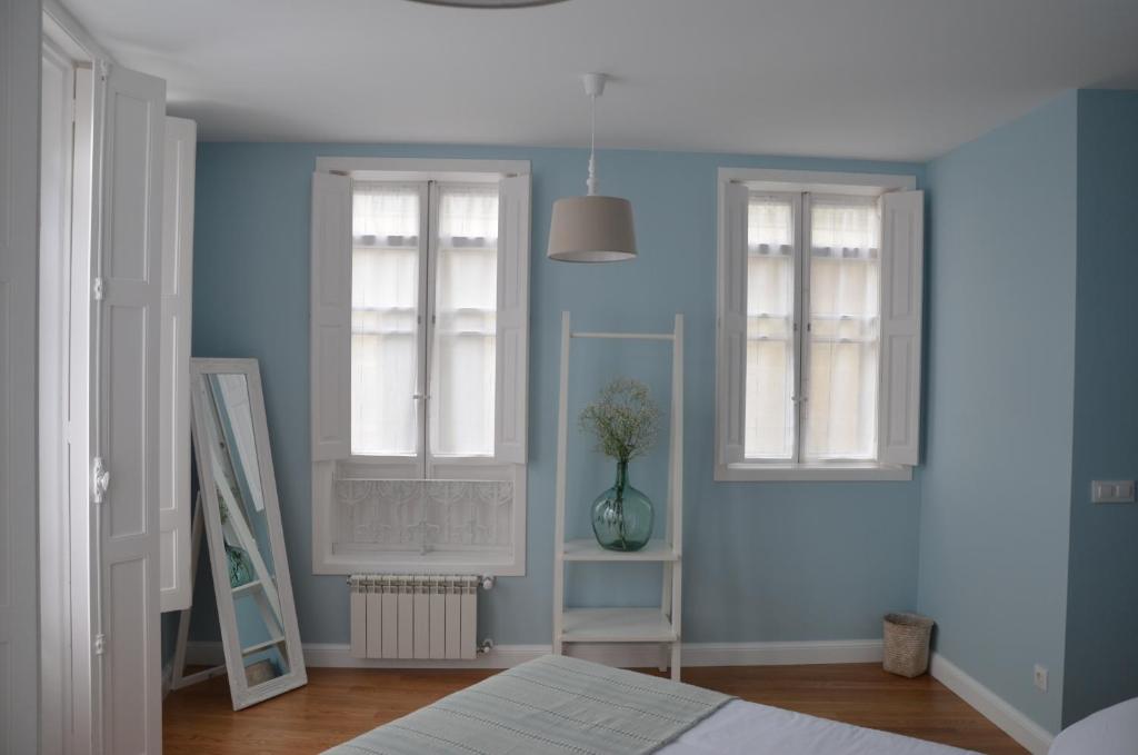 1 dormitorio con paredes azules, 2 ventanas y 1 cama en A Casa dos Nores Charming House en Cangas de Morrazo