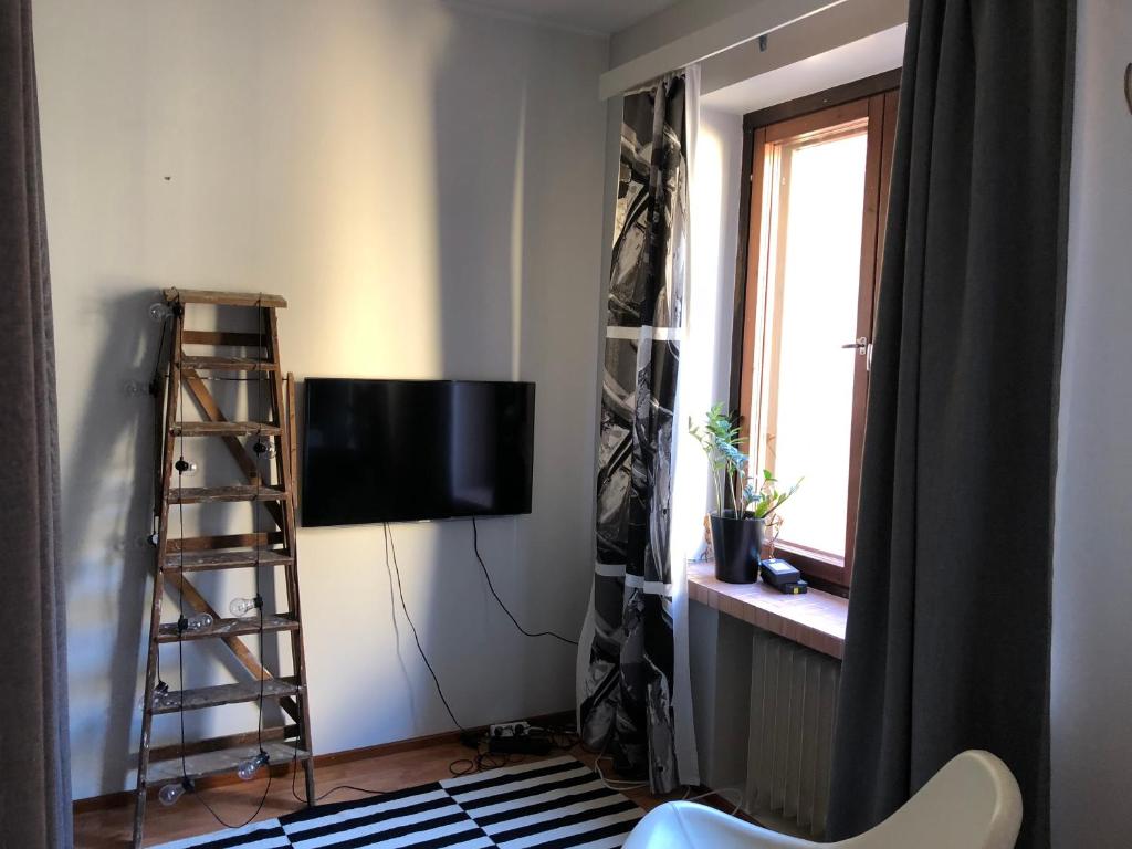 Cozy studio in Helsinki City Center في هلسنكي: غرفة معيشة فيها تلفزيون و سلم