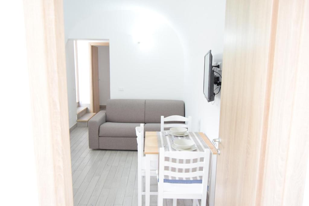 una sala de estar con un sofá, una mesa y sillas en Le Volte - Locazione Turistica, en Terrasini