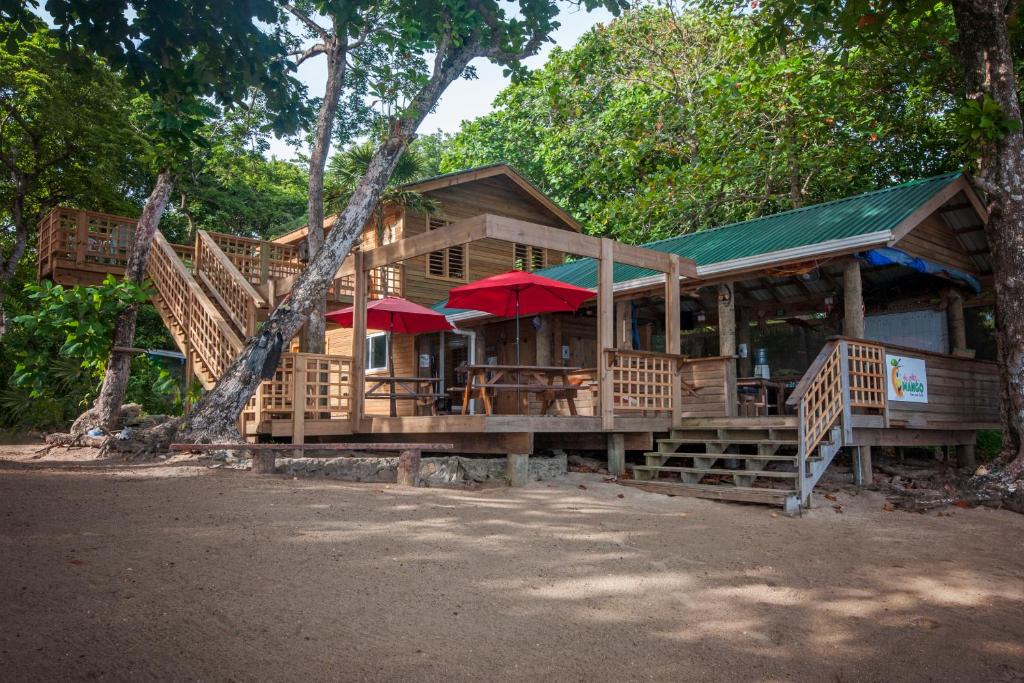 una grande casa in legno con scale e ombrelloni rossi di Casita Océana a Sandy Bay