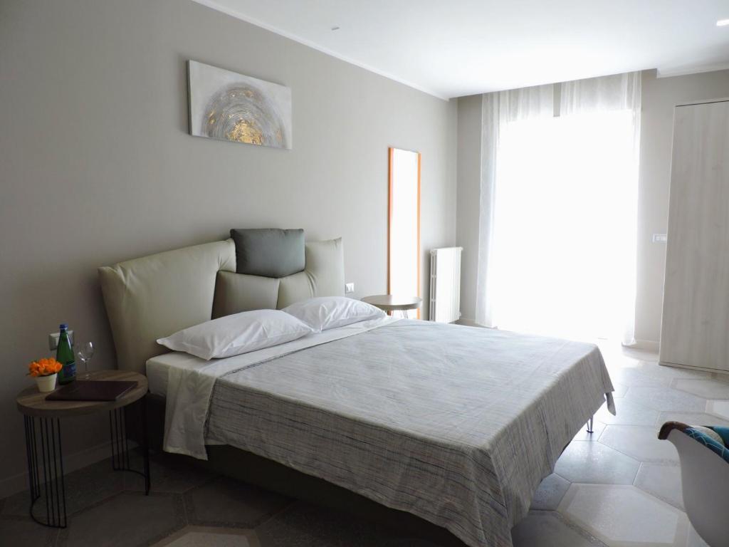 um quarto com uma cama com lençóis brancos e uma janela em Cilentorooms Paestum em Paestum