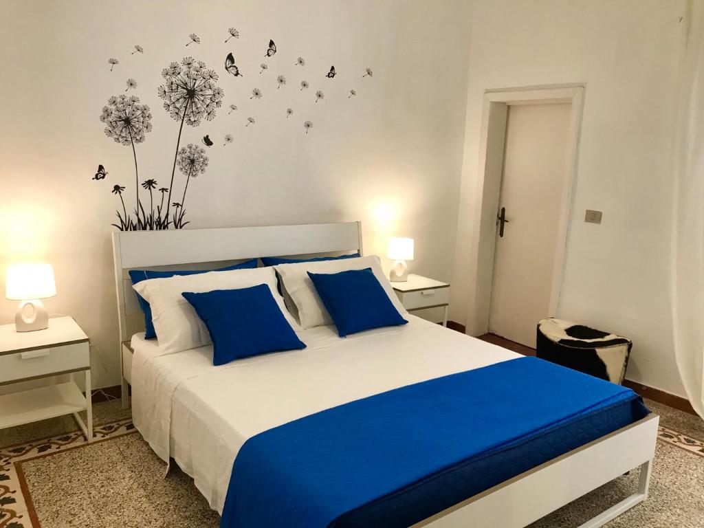 1 dormitorio con 1 cama con sábanas azules y dientes de león en la pared en Casa Vacanze Sonetto, en Maruggio