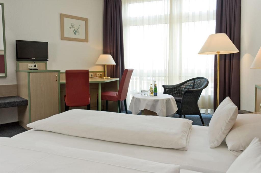 Habitación de hotel con cama, mesa y sillas en Apart' Hotel, en Kehl am Rhein
