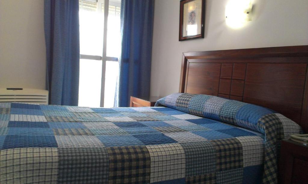 a bedroom with a bed with a checkered blanket at Hotel Marina Victoria in Algeciras