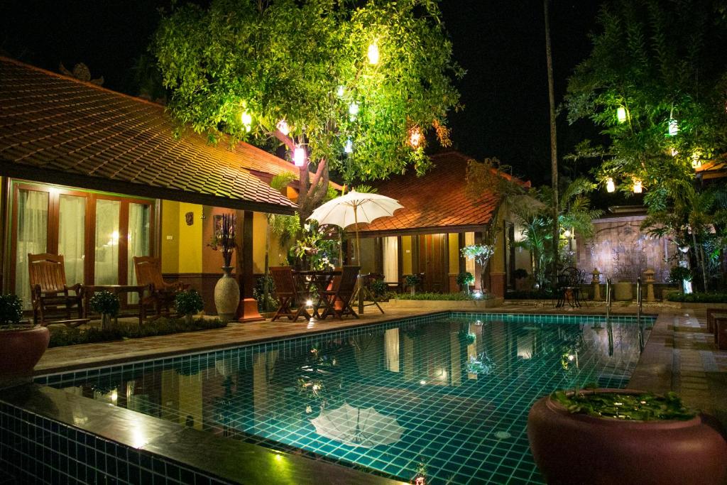 a swimming pool in front of a house at night at West Key Kamala Villa in Kamala Beach