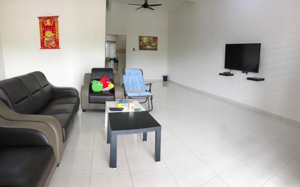 ein Wohnzimmer mit einem Sofa, Stühlen und einem TV in der Unterkunft My STW Home 2 in Sitiawan