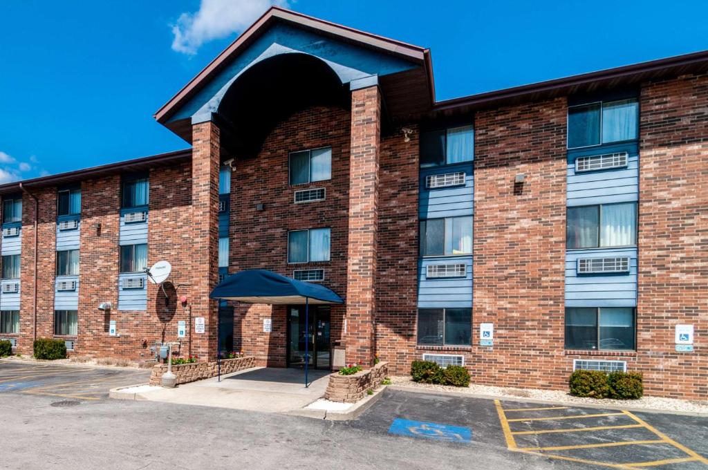 a brick building with an umbrella in a parking lot at Motel 6-Naperville, IL in Naperville