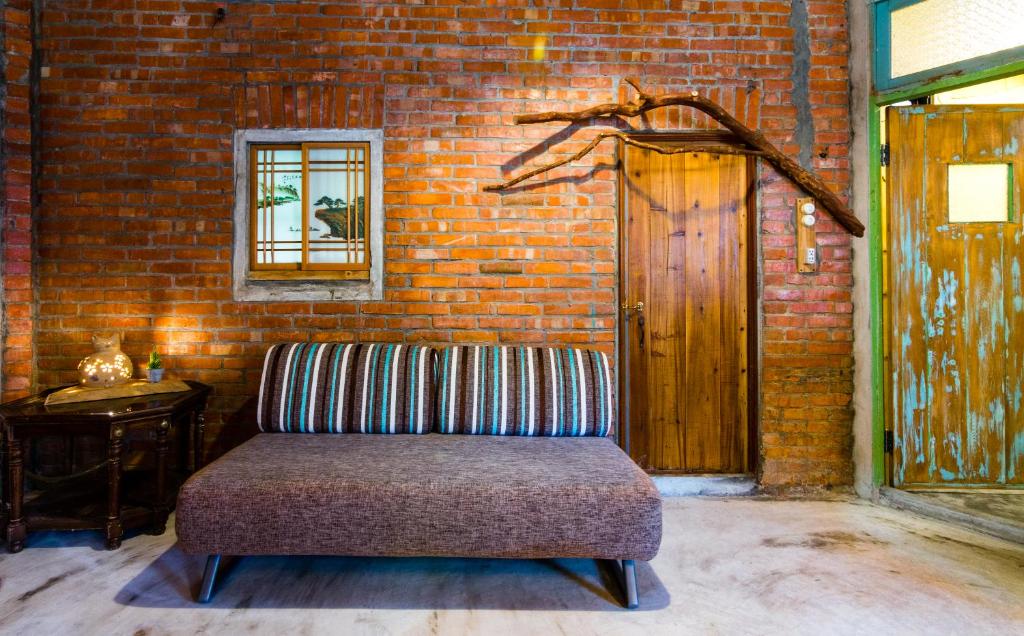 a couch sitting in a room with a brick wall at Lungta BnB in Jiufen