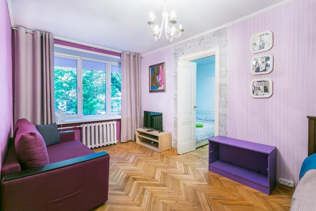 モスクワにあるАпартаменты на Малой Пироговской 6/4の紫色のソファが備わるウッドフロアのリビングルーム