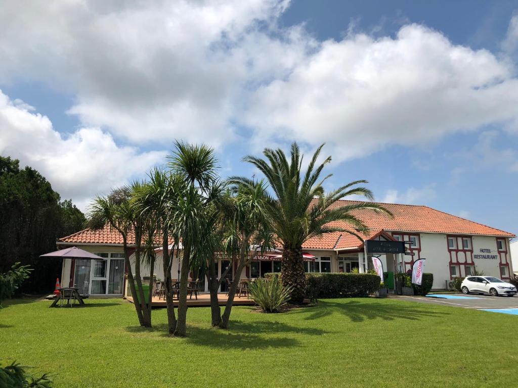 uma casa com palmeiras em frente a um quintal em FastHôtel Biarritz Bidart Côte-Basque - Un hôtel FH Collection em Bidart