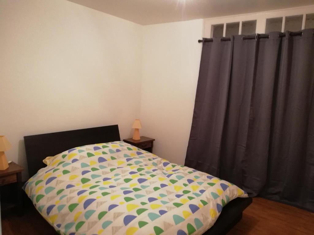 um quarto com uma cama com um edredão colorido em Gîte chez Effat em Saint-Aignan